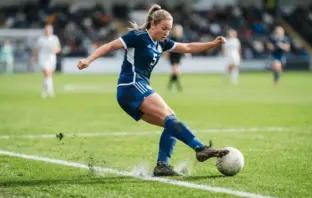 Women's football defender in action on green pitch with white markings