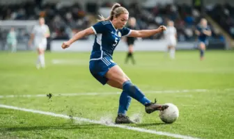 Women's football defender in action on green pitch with white markings