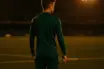 Young footballer on pitch at dusk under floodlights contemplating career move