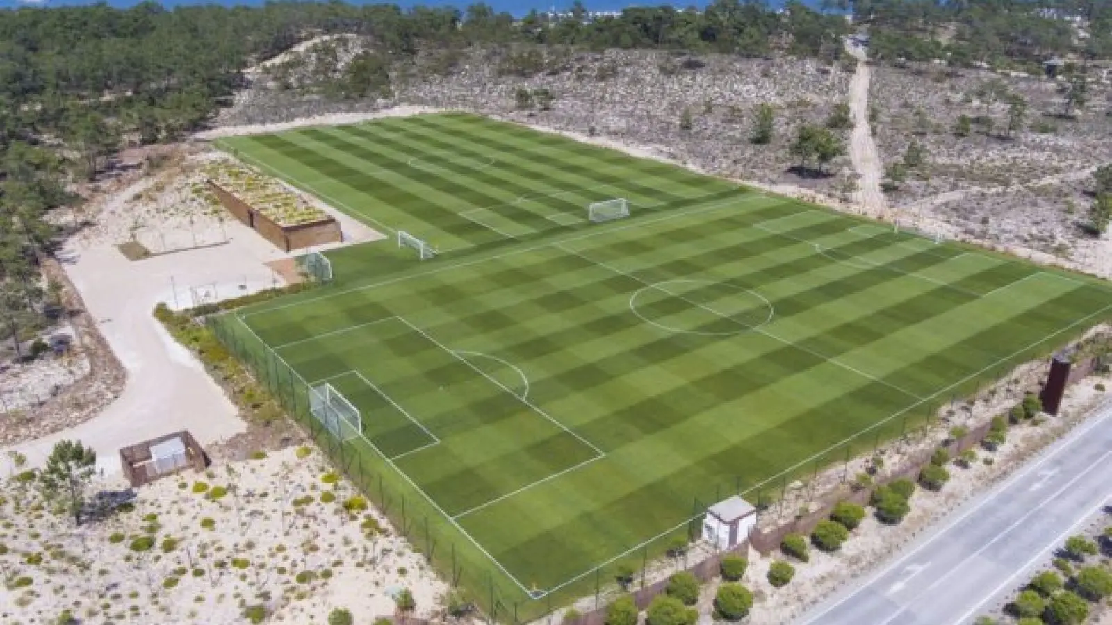 Aerial view of a well-maintained football training pitch surrounded by trees.