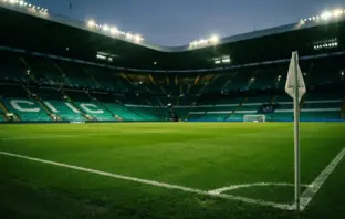Empty football stadium with Celtic green lighting at dusk before Champions League play-off match