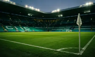 Empty football stadium with Celtic green lighting at dusk before Champions League play-off match