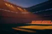 Floodlit stadium at golden hour with packed stands, dramatic shadows, Swiss red and Colombian colours in atmospheric haze.