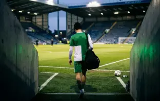 Young centre-back entering a floodlit stadium for a season-long development loan
