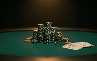 Stacked green and white poker chips on a deep green felt table, cinematic editorial lighting.