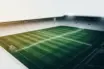 Green-and-white football pitch under stadium lights symbolising Celtic’s rescheduled league fixtures and Europa League schedule.