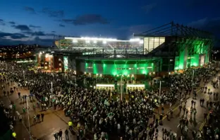 Celtic Park glowing green at night as supporters arrive for a crucial Champions League play-off