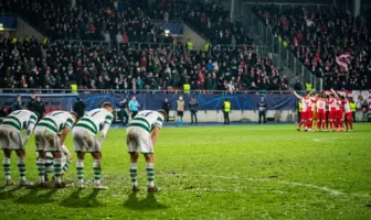 Dejected Celtic-inspired players react after a dramatic European football collapse in a floodlit stadium
