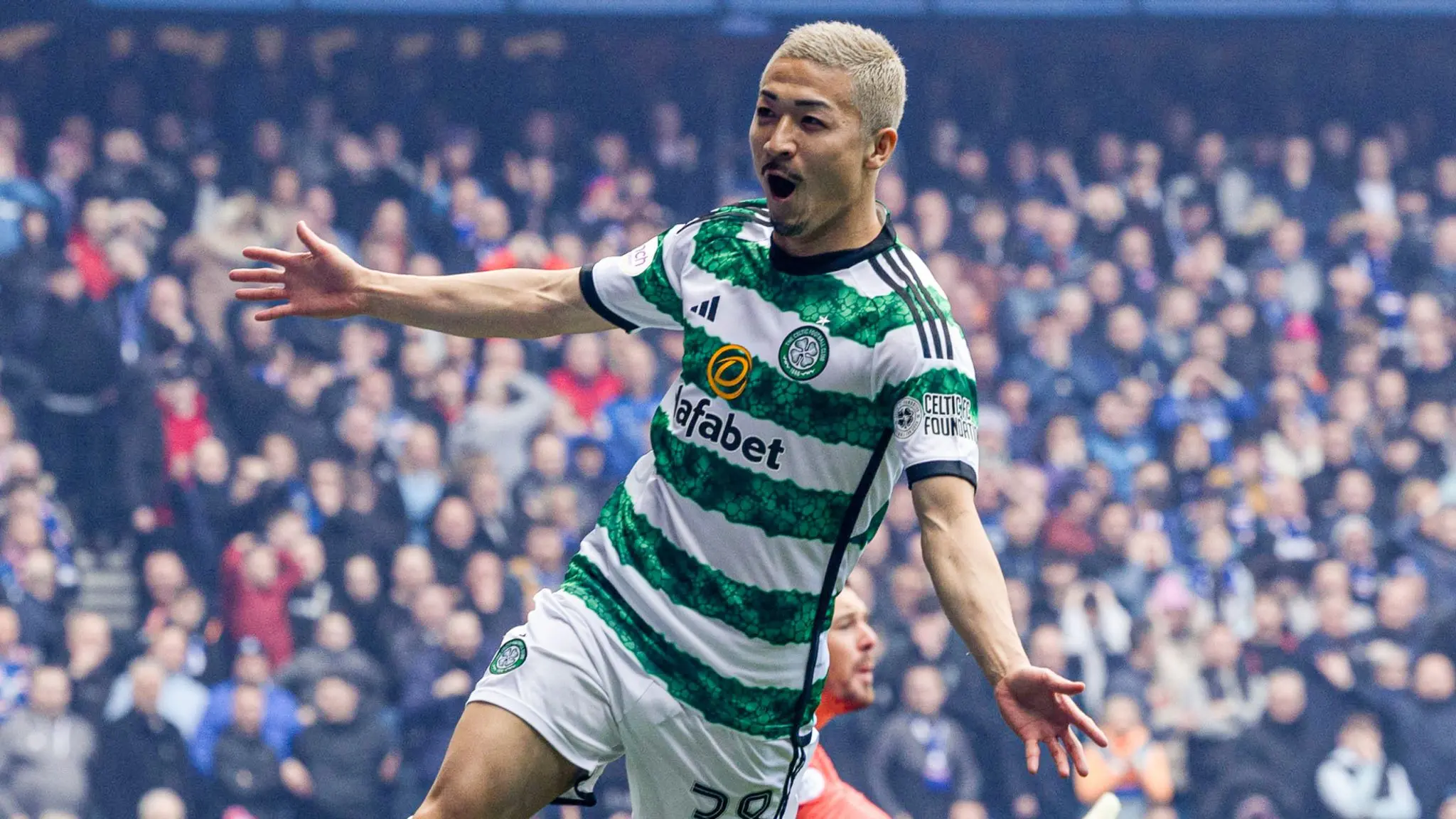 Daizen Maeda celebrating in a green and white hooped Celtic FC kit during a match