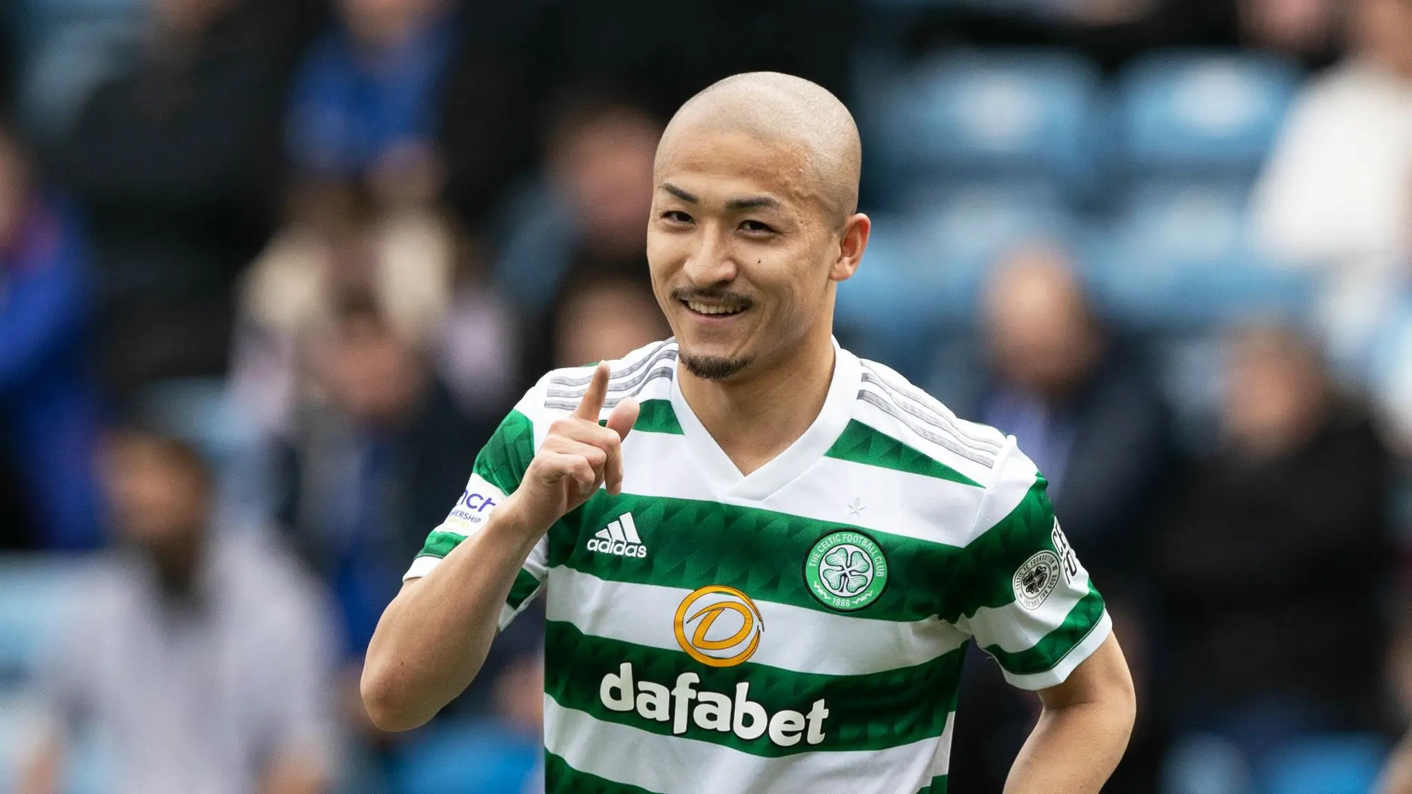 Daizen Maeda in a green and white hooped Celtic FC jersey celebrating on the pitch