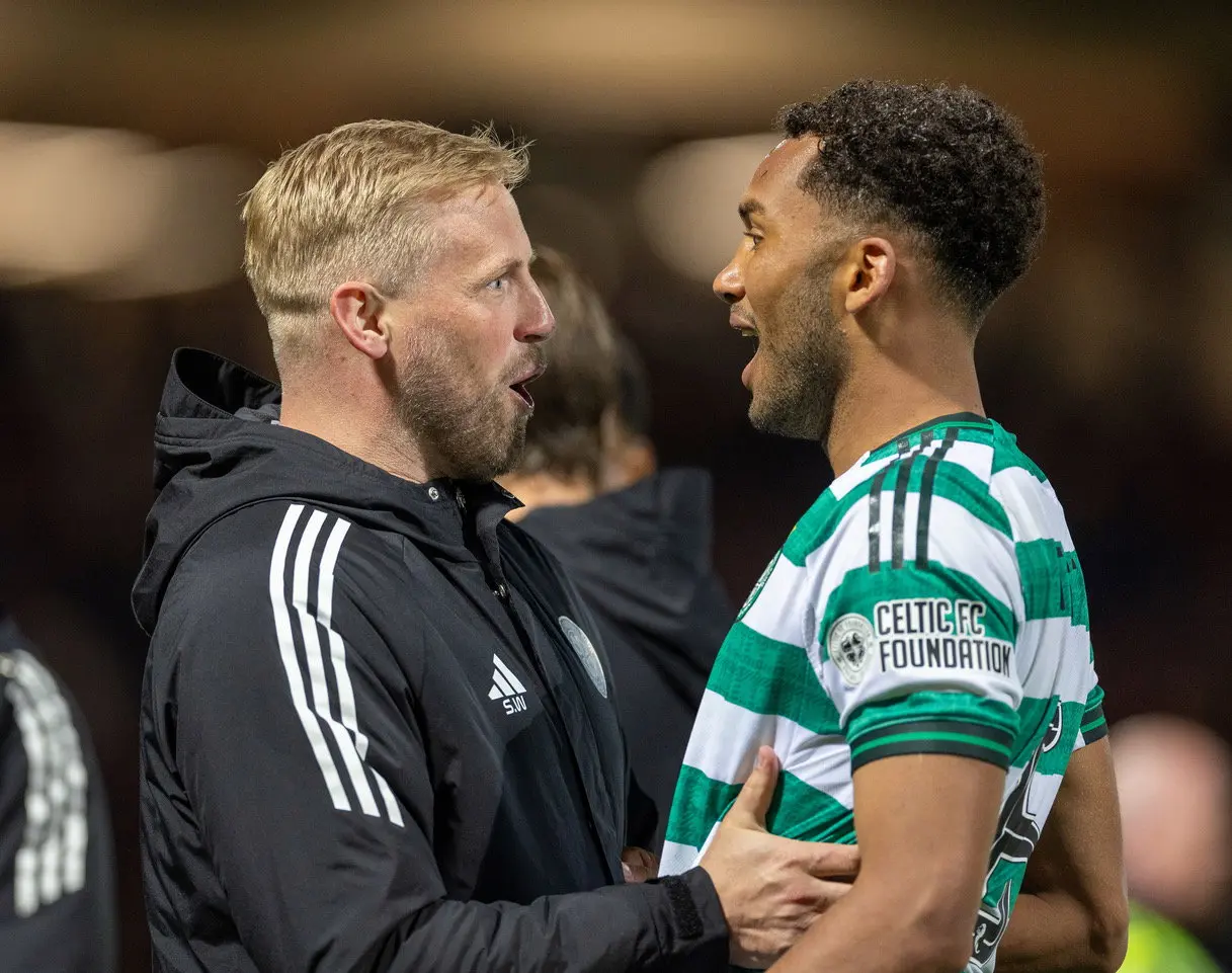 Kasper Hogh in a green and white striped Celtic FC jersey talking to a coach in a black jacket.
