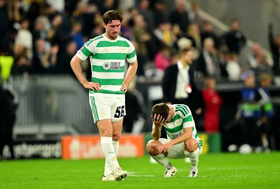 Two Celtic FC players in green and white striped jerseys looking disappointed on a football pitch