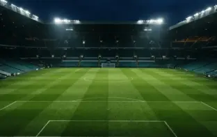 Celtic Park stadium pitch illuminated under floodlights at night before a Champions League match