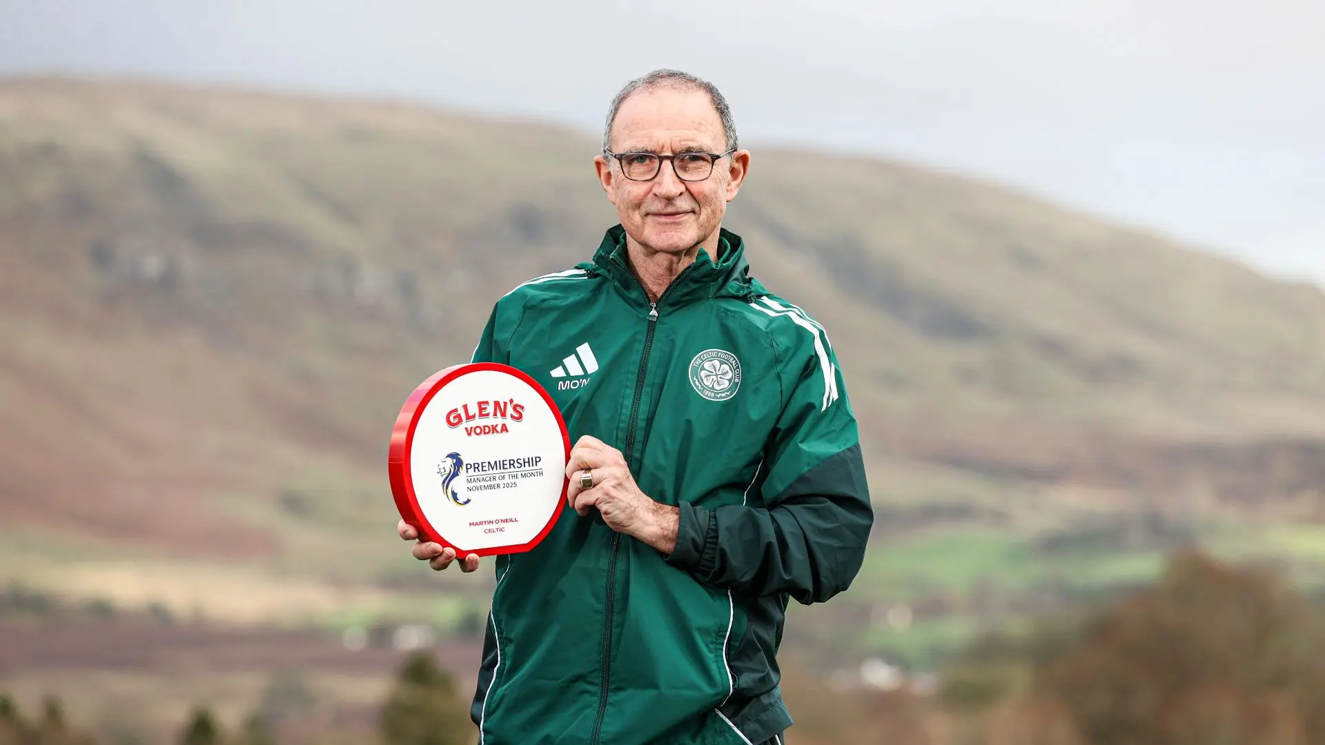 Martin O'Neill in a green Celtic FC jacket holding a Glen's Vodka Premiership Manager of the Month award