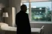 Respectful silhouette of a football manager near a hospital window with a softly lit stadium beyond