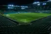 Stadium clock showing added time beyond 45 minutes with yellow card on pitch under floodlights