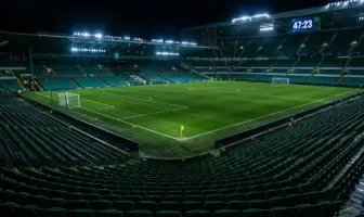 Stadium clock showing added time beyond 45 minutes with yellow card on pitch under floodlights