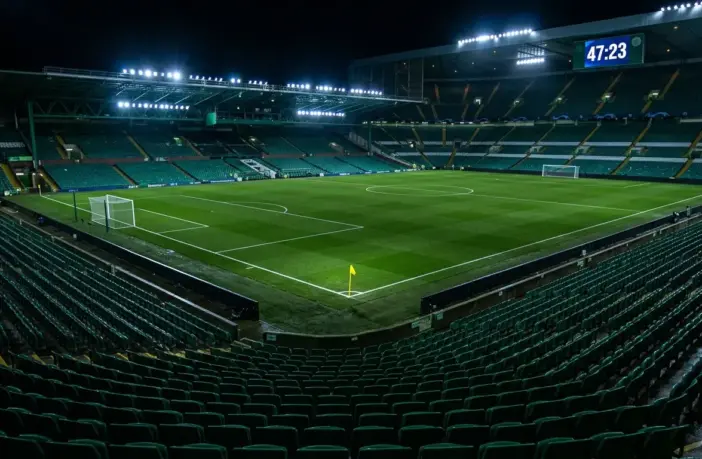 Stadium clock showing added time beyond 45 minutes with yellow card on pitch under floodlights