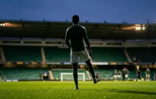Celtic-inspired midfielder silhouette training under stadium lights ahead of a derby quarter-final