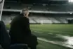 Older football manager silhouette reflecting alone in a stadium after a difficult week
