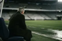 Older football manager silhouette reflecting alone in a stadium after a difficult week