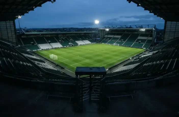 Empty football stadium under floodlights symbolising Celtic’s financial setback after a Champions League exit