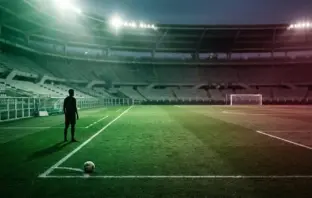 Football transfer dispute symbolised by a midfielder silhouette between green and burgundy stadium light