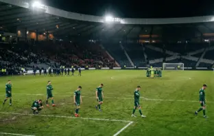 Fragmented Celtic players on a floodlit pitch after a derby defeat