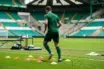 Anonymous Celtic-green footballer completing a controlled rehabilitation drill on a training pitch