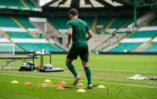 Anonymous Celtic-green footballer completing a controlled rehabilitation drill on a training pitch