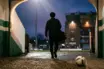 Silhouetted midfielder leaving a green-and-white stadium for a new English football club