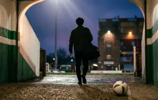 Silhouetted midfielder leaving a green-and-white stadium for a new English football club